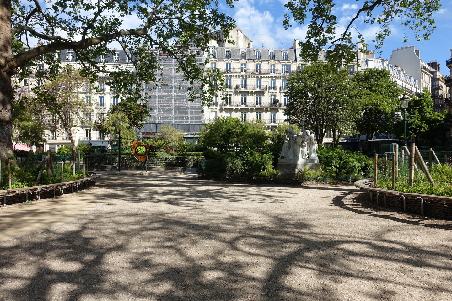 A view of Square Montholon, including the statue Les statues des Catherinettes by Julien Lorieux, as well as benches and garden space.<br />