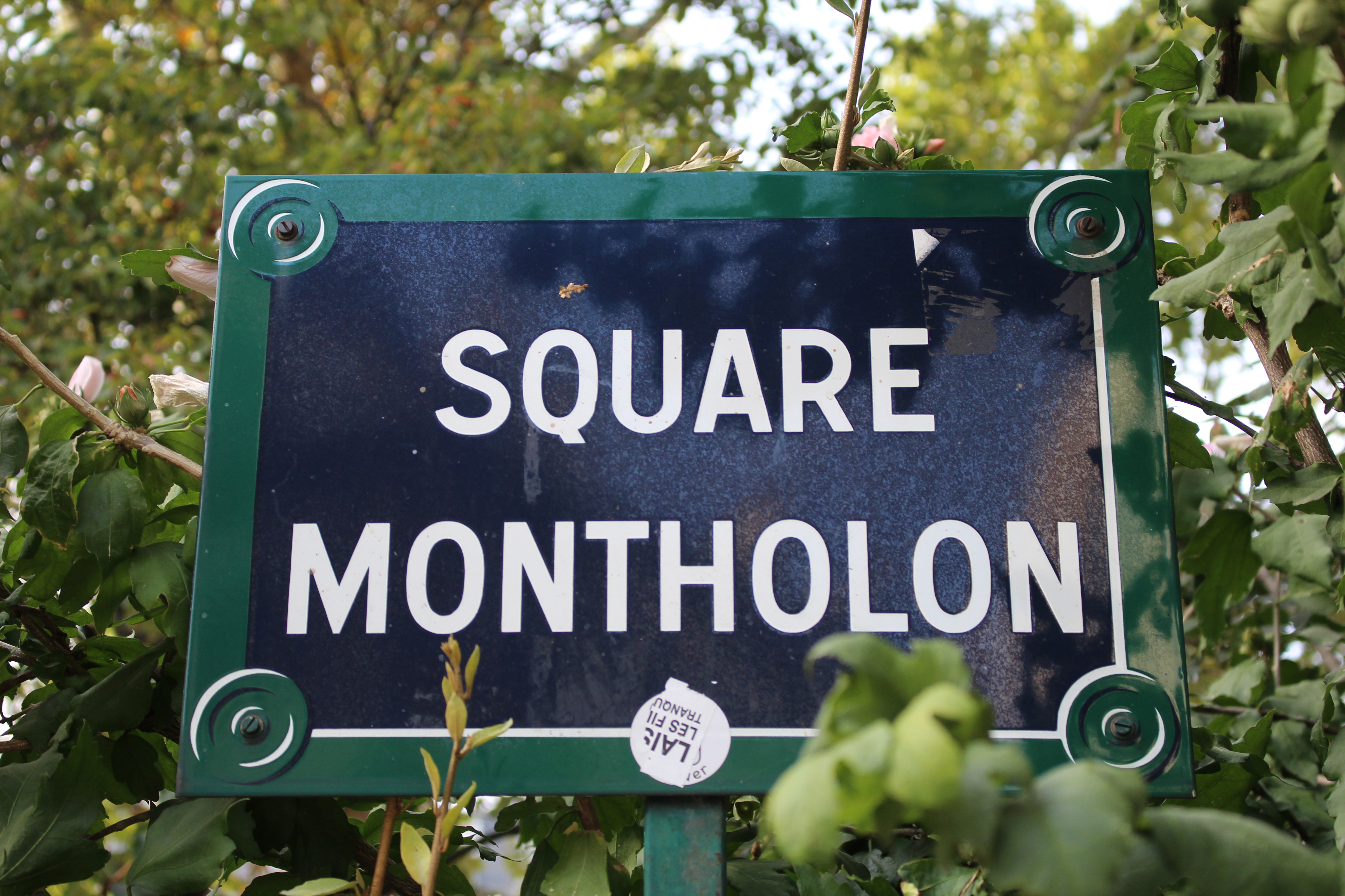 A photo of a sign for Square Montholon, surrounded by plants.